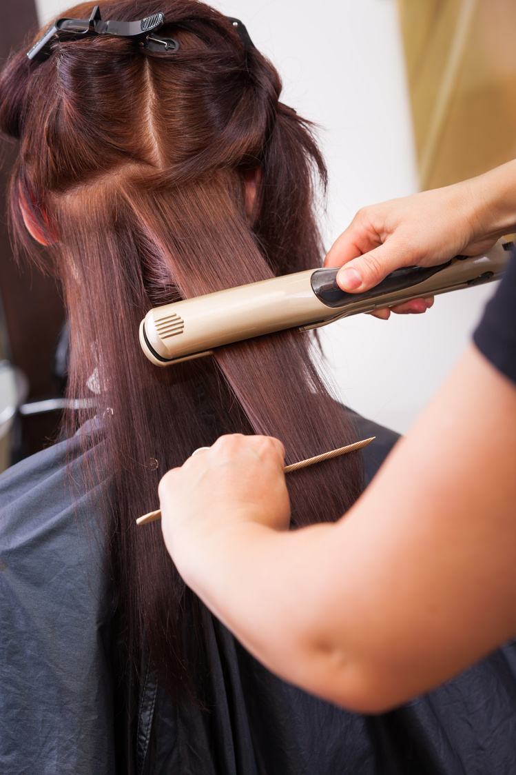 Hairdresser straightening hair with hair straightener